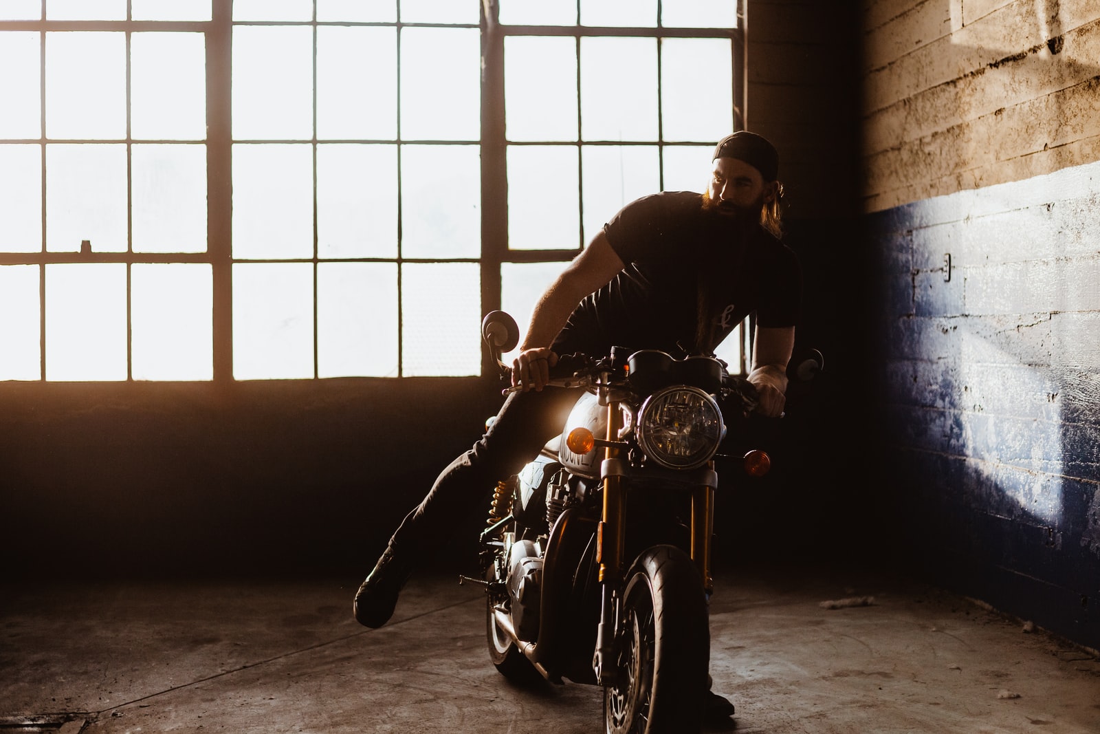 Homme barbu avec sa moto a l'intérieur d'un garage